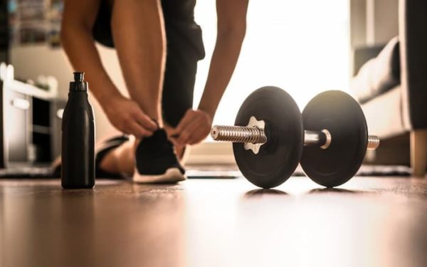 Man tying shoelaces with weights in his bedroom